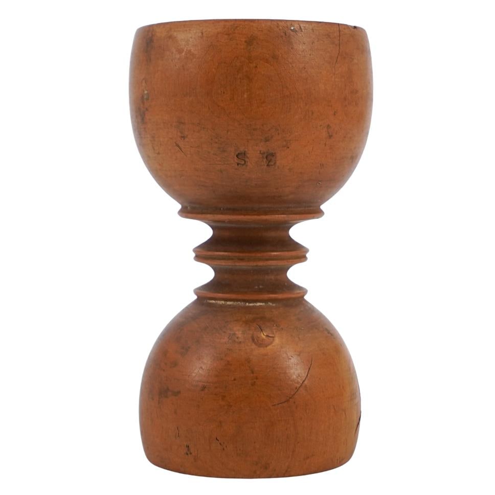 Wooden Double Egg Cup: Wooden Double Egg CupEarly 20th century, EuropeanA wooden egg cup with two egg resting sides, one is smaller than the other. Natural texture and decoratively carved tapering stem between rests.L 3 1/2