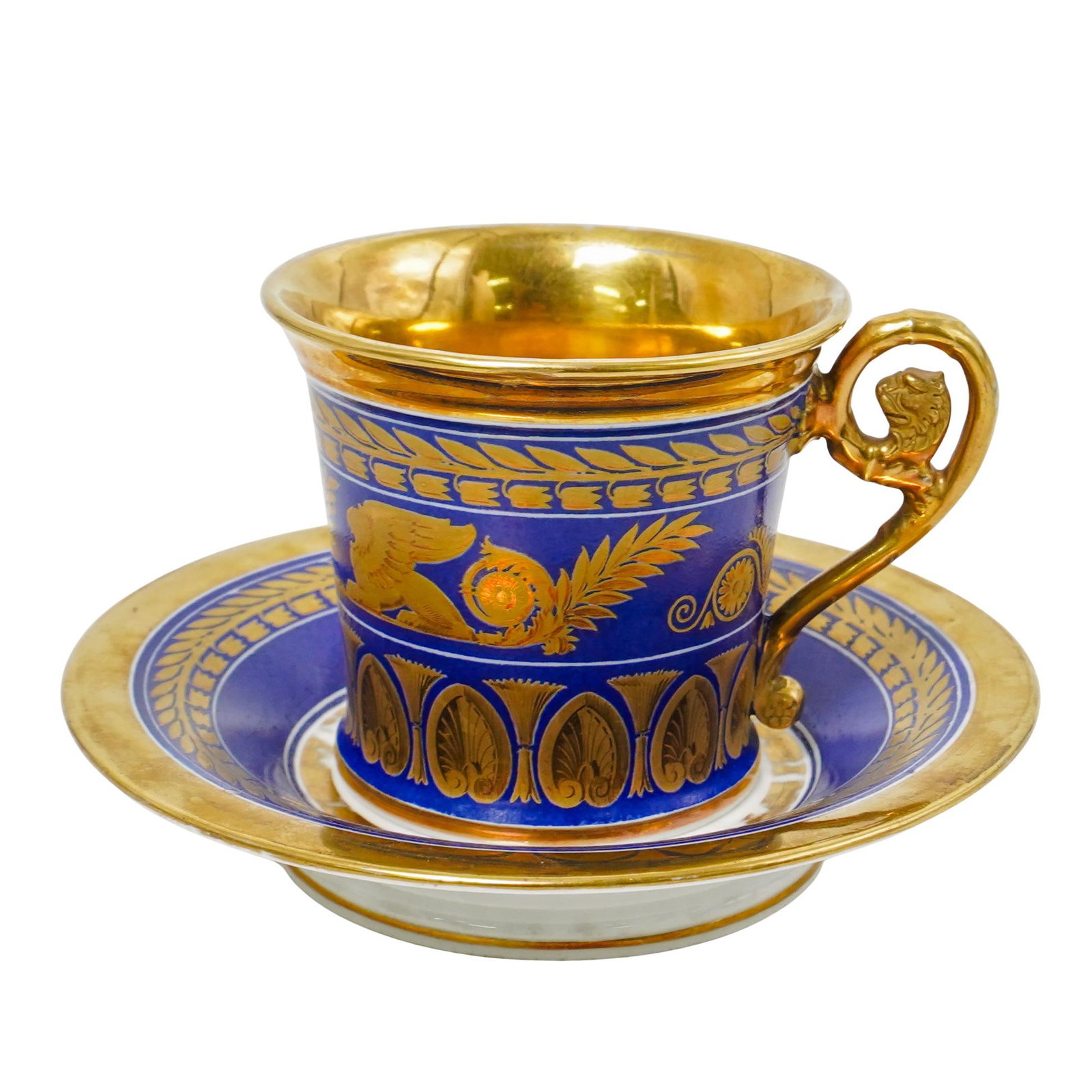 Empire Style Cobalt and Gilt Porcelain Cup and Saucer: Empire Style Cobalt and Gilt Porcelain Cup and Saucer 19th century An empire style porcelain cup and matching saucer in a cobalt blue with hand-painted gilt accenting and a decoratively carved handle.