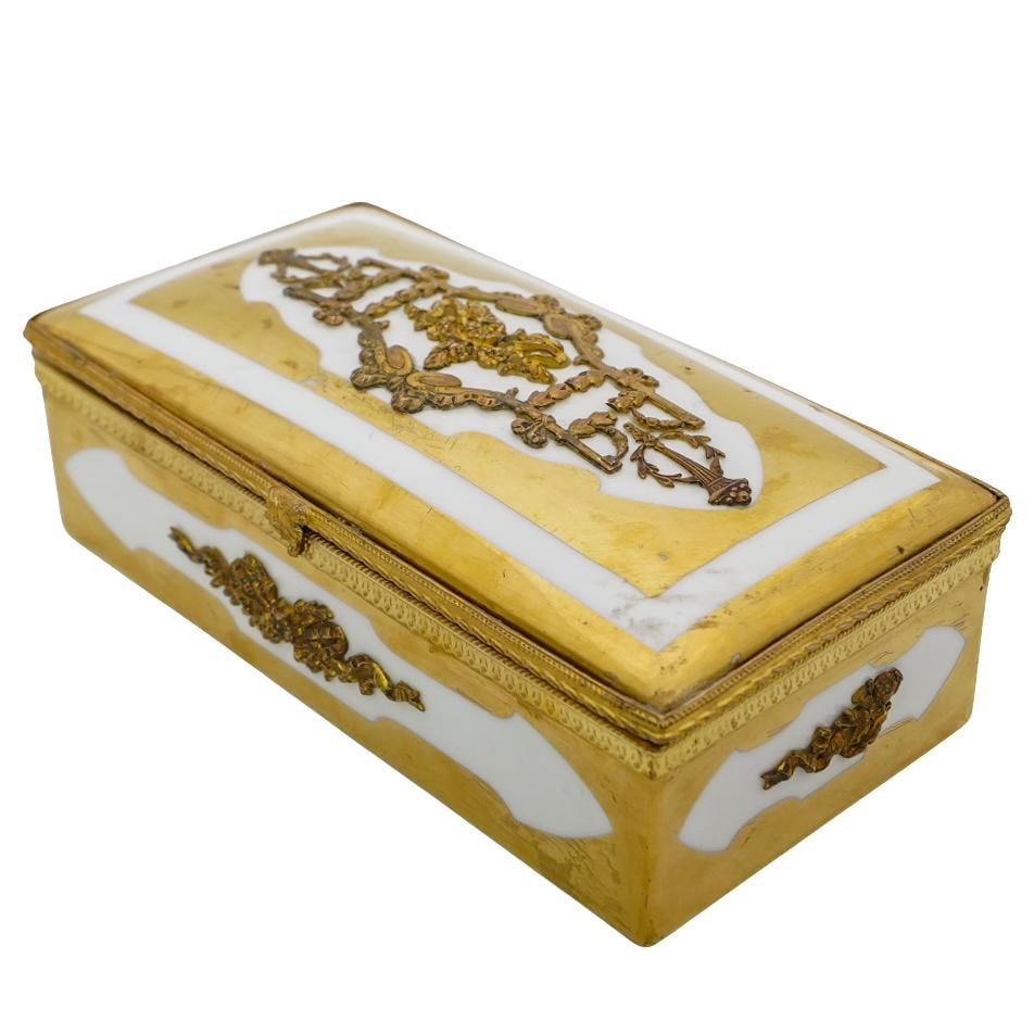 Gilded Porcelain Box: Gilded Porcelain Box 20th c., Continental White porcelain box with ornate gilded floral decorations and gilt trim. Stylized floral trident affixed to the inside of the lid. Approx. H: 2.75" W: 4" L: 7