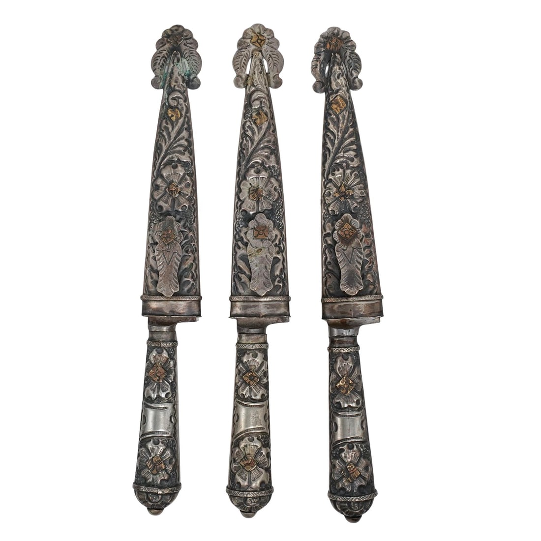 (3 pc) Argentinian Alpaca Daggers and Sheaths: (3 pc) Argentinian Alpaca Daggers and Sheaths20th century, ArgentinaA trio of Argentinian Alpaca silver knives with gilt accents and a floral carved design on hilt and sheaths. Marked on blade: "JU-CA
