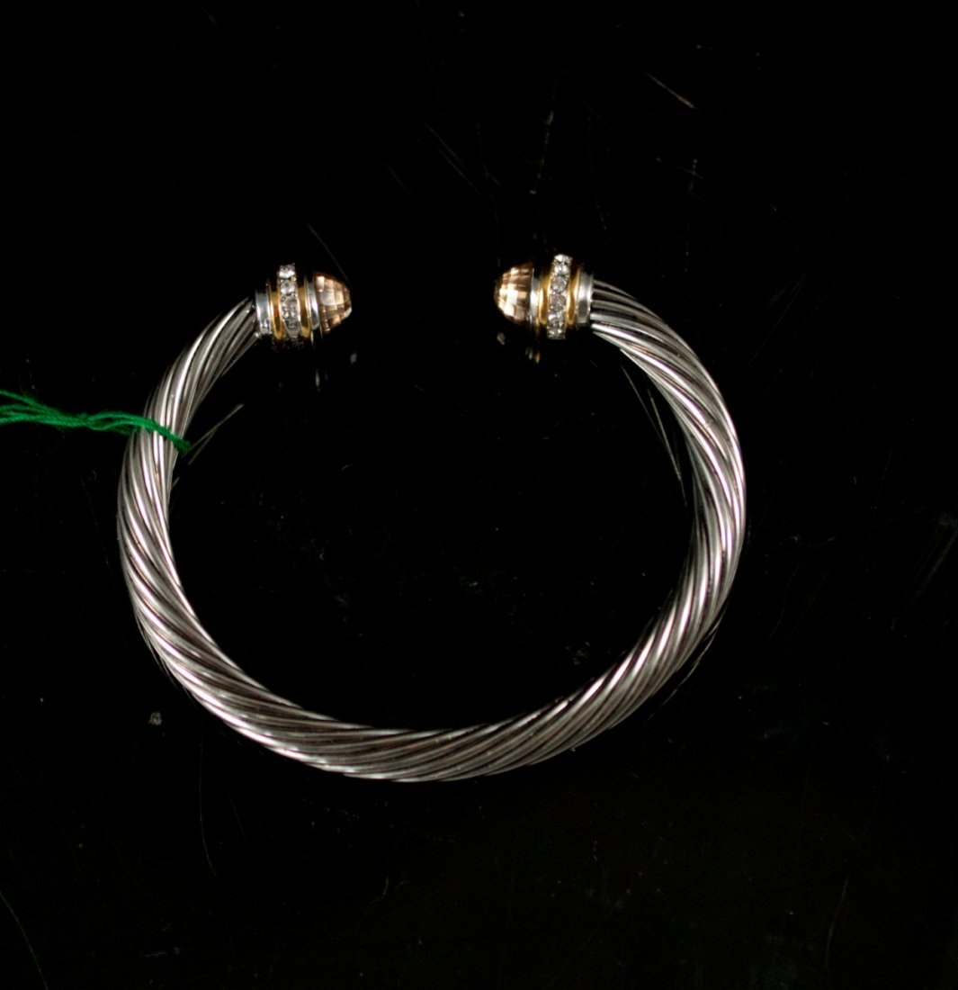 David Yurman style bangle bracelet: DESCRIPTION: David Yurman style bangle bracelet. Features a stainless steel twisted design. Each end is capped with small rhinestones, 18k gold accent and two faceted cabochon stones with a pink hue. 