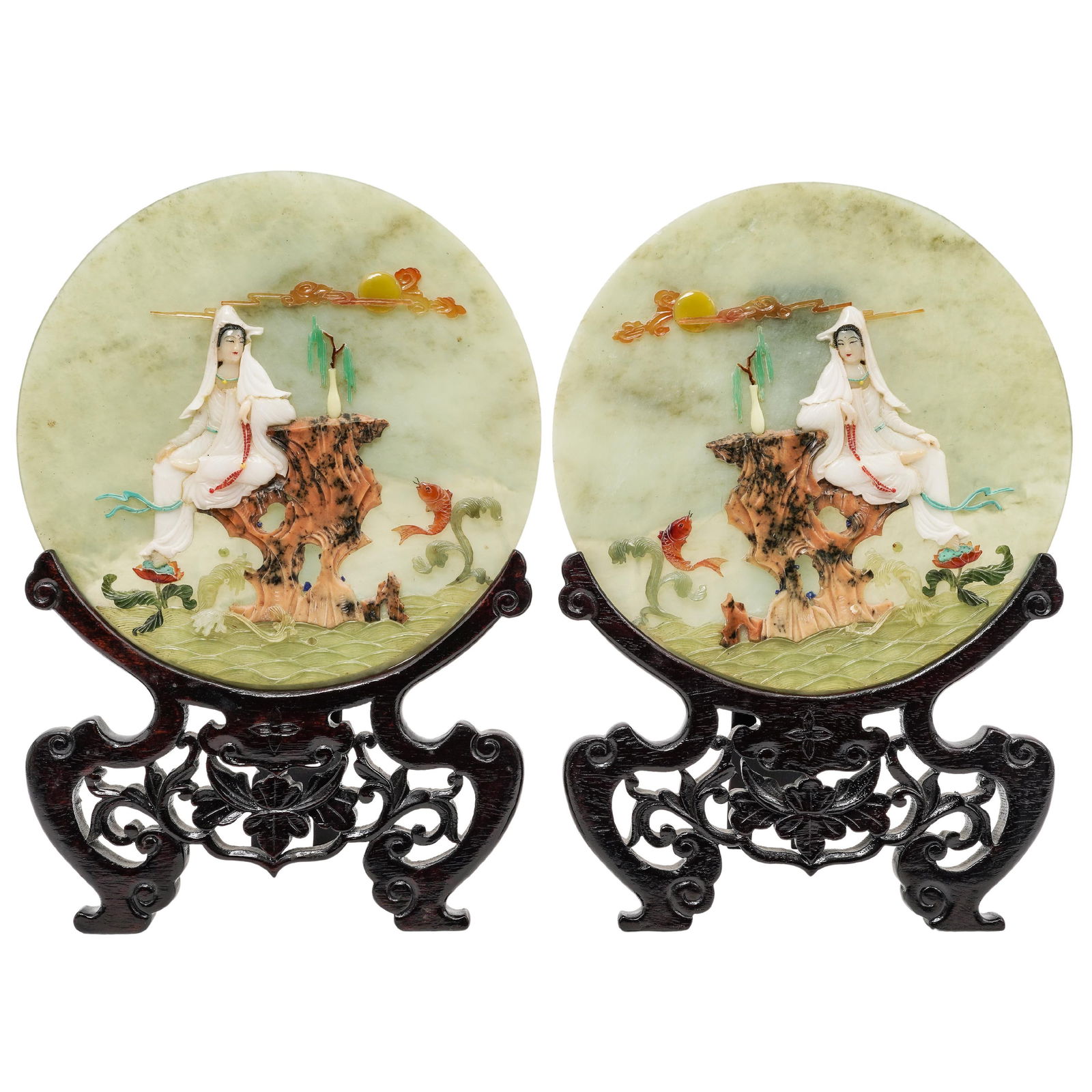 Pair Of Chinese Jade Plaques With Wood Stands: Pair Of Chinese Jade Plaques With Wood StandsMid 20th Cent., ChinesePair of Chinese carved jade and hard stone relief circular plaques, each depicting a seated Guanyin figure resting on a rocky outcro