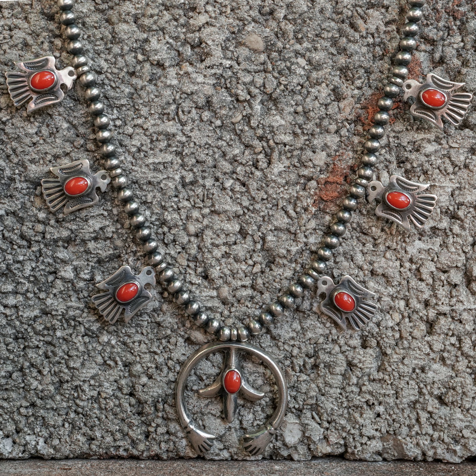 Navajo Sterling Silver & Coral Necklace: Navajo Sterling Silver & Coral Necklace Circa 1970s–1980s, USA. A vintage Navajo sterling silver squash blossom necklace featuring six blossoms and a traditional naja, each set with a coral cabochon
