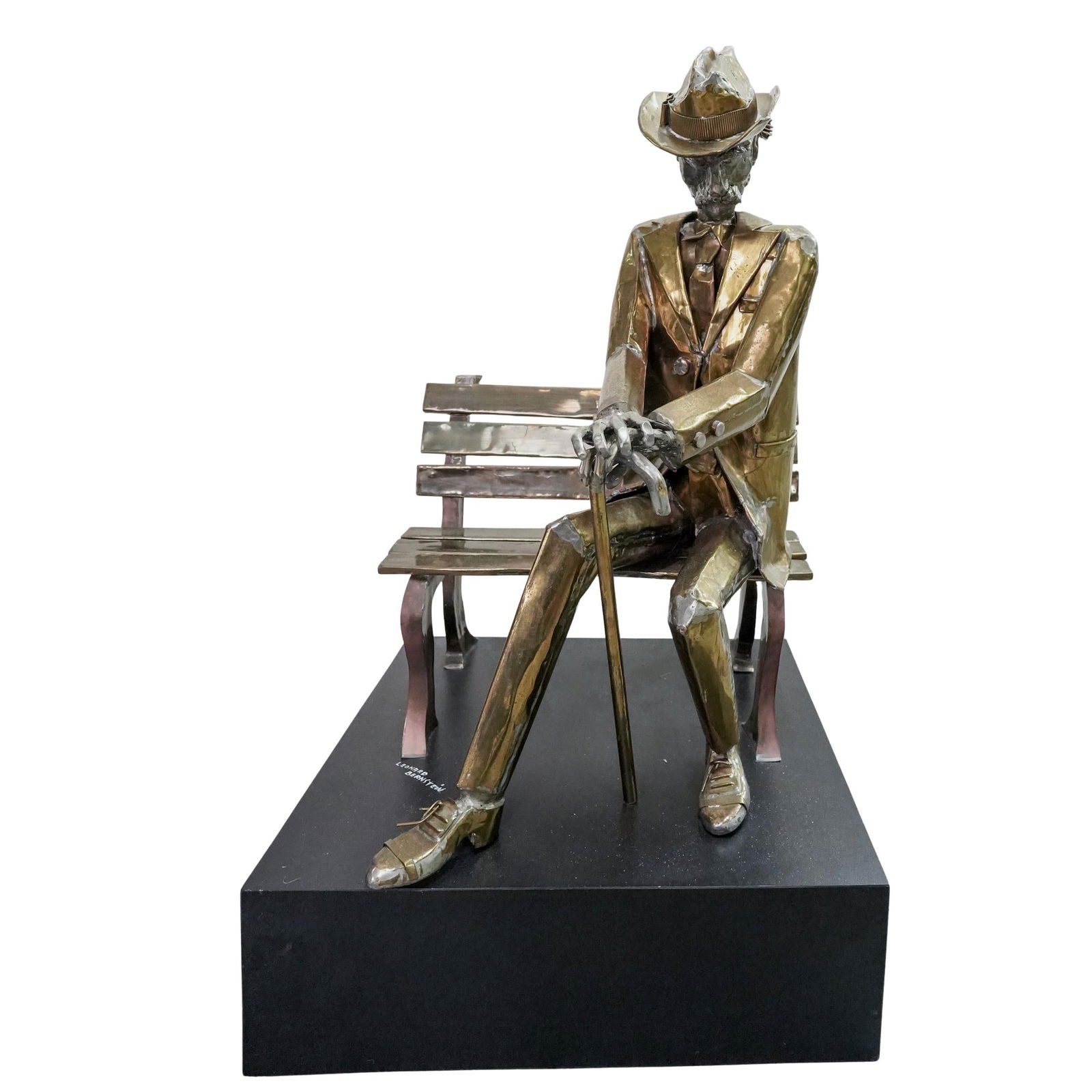 Leonard Bernstein Brass Seated Figure Sculpture: Leonard Bernstein Brass Seated Figure SculptureLate 20th century.A hand welded gilt brass sculpture of a seated male figure with a cane on a park bench. Affixed to a black composite base. Base signed