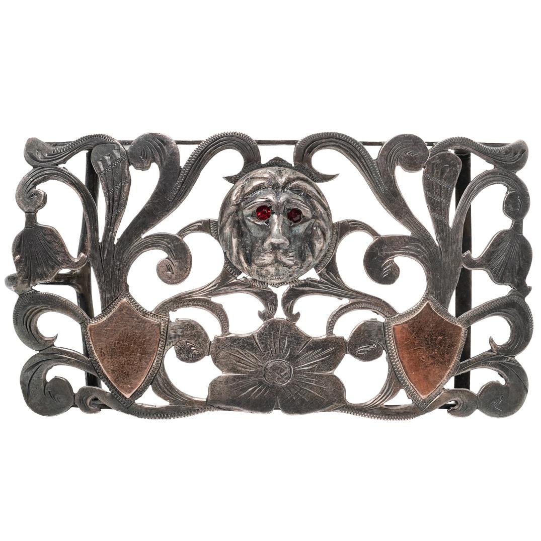 Antique Mexican Sterling Silver Lion Belt Buckle: Antique Mexican Sterling Silver Lion Belt BuckleCirca 20th Century, MexicanSterling silver belt buckle of rectangular openwork form, centered by a sculpted lion’s head in high relief with red stone