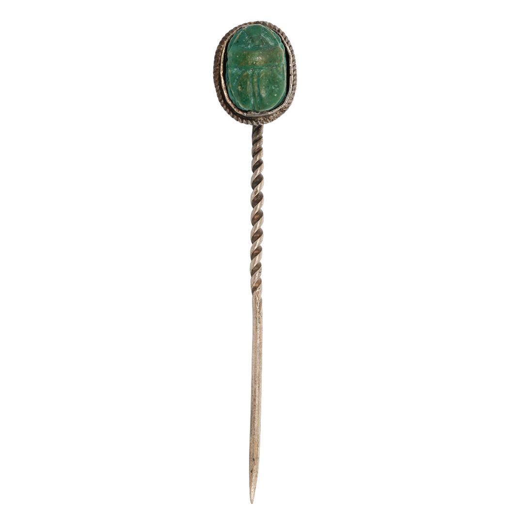 Egyptian Revival Silver Scarab Stick Pin: Egyptian Revival Silver Scarab Stick Pin Circa Late 19th - early 20th century Elongated silver stick pin surmounted by a carved green scarab cabochon. The scarab is bezel-set within a rope-twist