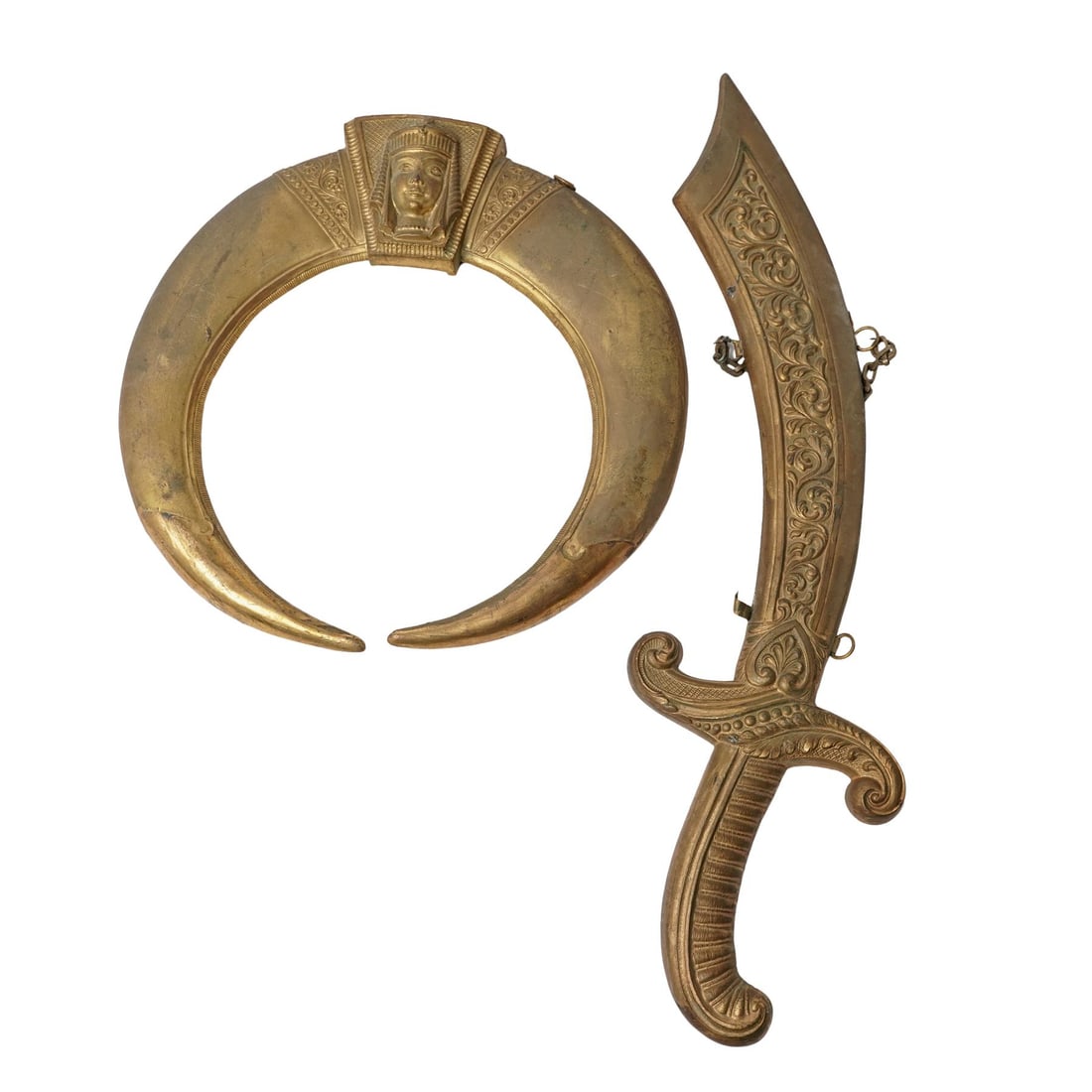 (2 pc) Art Metal Works Hanging Ornaments: (2 pc) Art Metal Works Hanging OrnamentsMid-20th century, USALot of two , the large, crescent-shaped mirror features an embossed face of Egyptian pharaoh head at the apex. The curved sword is known as