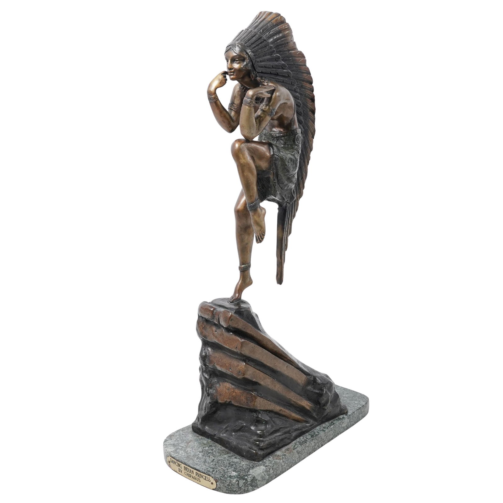 After Demetre Chiparus "Dancing Indian Princess" Bronze Sculpture: After Demetre Chiparus "Dancing Indian Princess" Bronze SculptureMid 20th c., USACast patinated bronze statue depicting a Native American woman in a poised, dancing stance, adorned with a feathered he