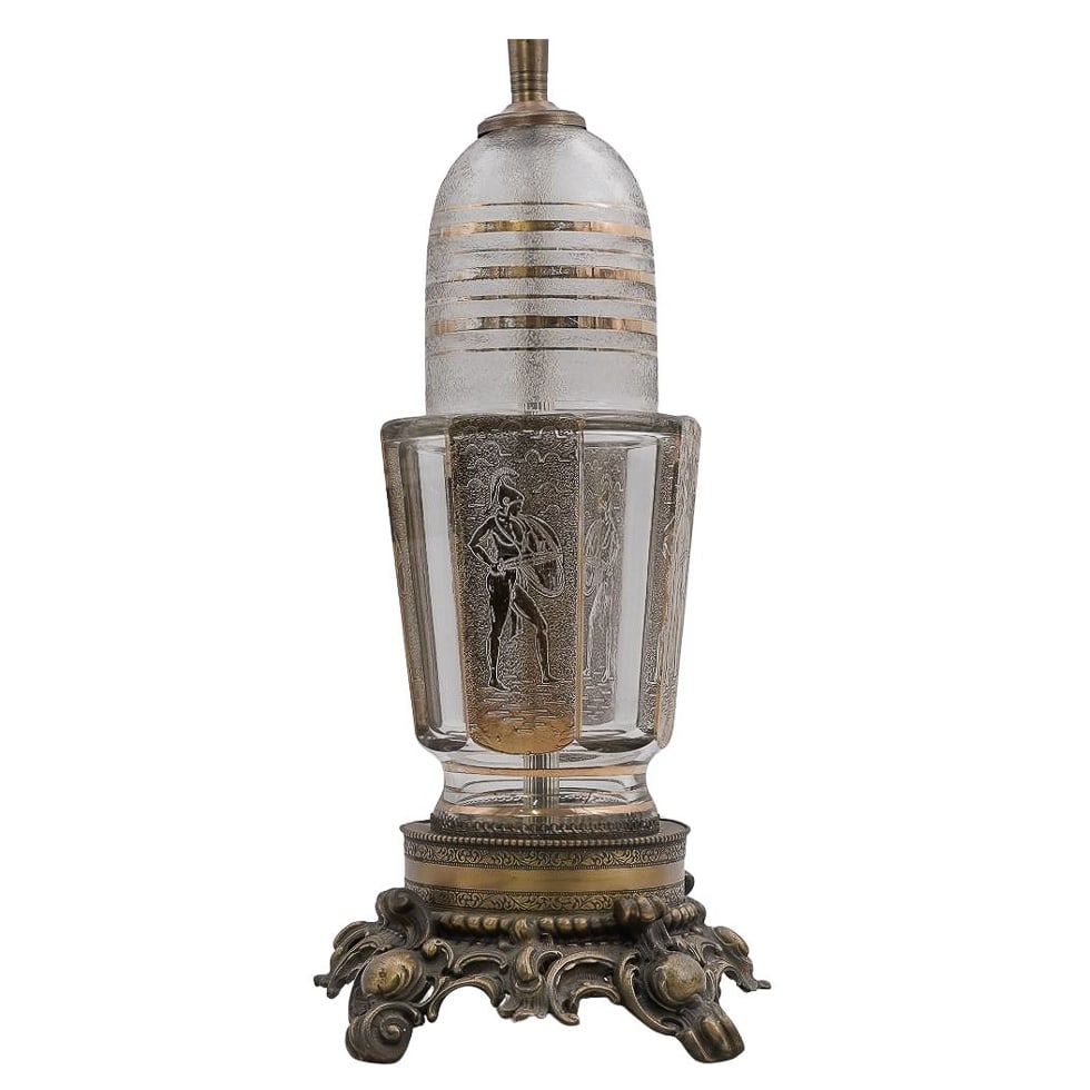 Vintage Hollywood Regency Etched Crystal Lamp: Vintage Hollywood Regency Etched Crystal Lamp 20th century A vintage Hollywood Regency style table lamp featuring an ornate brass base, a glass body with etched Neoclassical figures, and an ornately