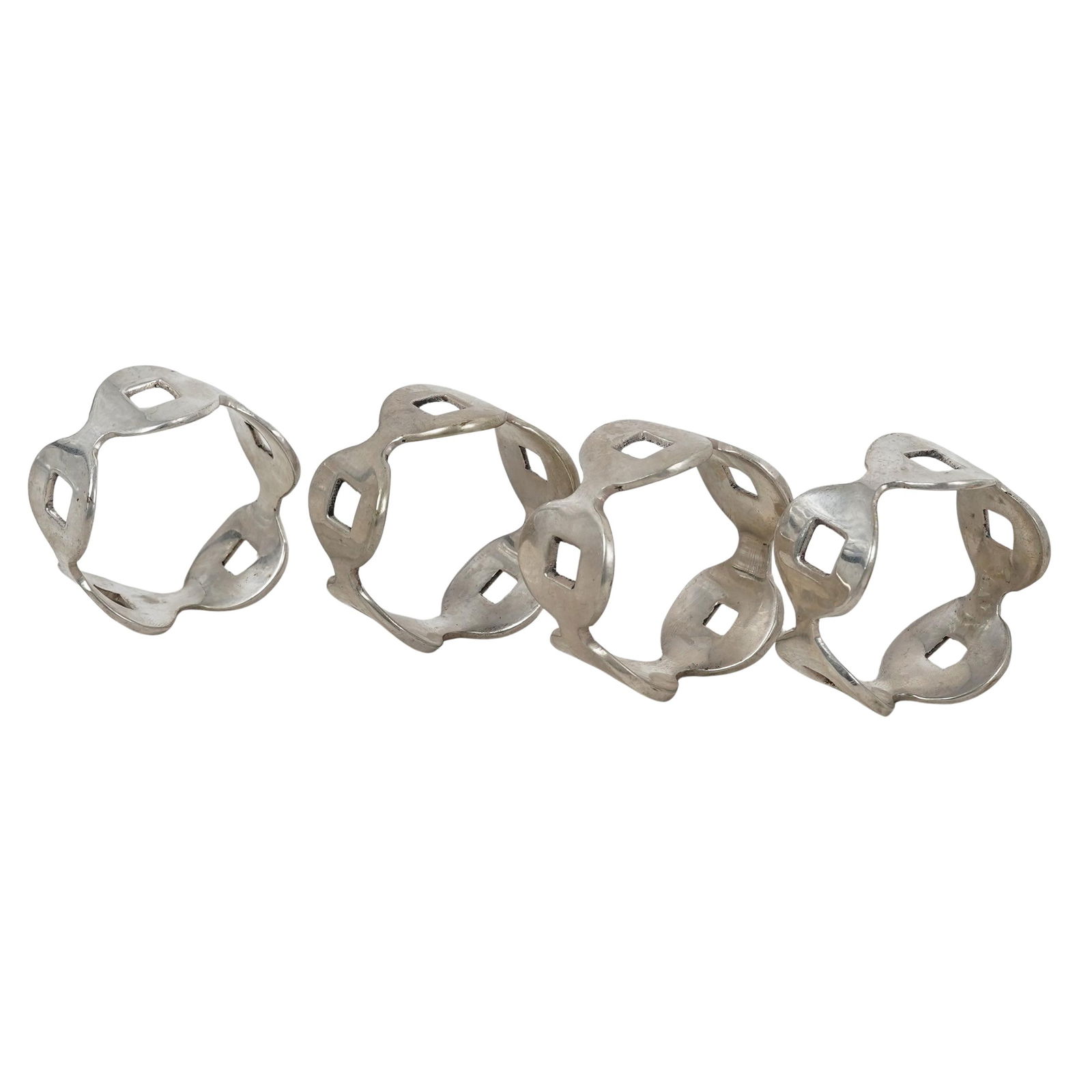 (4 Pc) Silver Plated Geometric Napkin Rings: (4 Pc) Silver Plated Geometric Napkin Rings Late 20th century Silver metal napkin rings featuring geometric patterns. H: 1" Dia: 2"