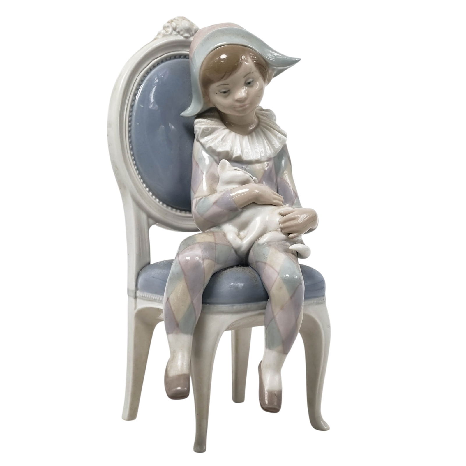 Lladro "Young Harlequin" Porcelain Figurine: Lladro "Young Harlequin" Porcelain Figurine1972-1999, SpanishGlazed porcelain figurine, hand-painted in soft pastel colors, depicting a young boy dressed as a harlequin, seated on a large chair and ho