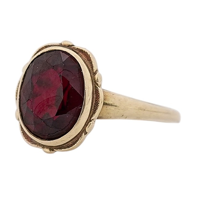 Vintage 10k Gold Garnet Ring Signed: Vintage 10k Gold Garnet Ring Signed Late 20th Century, USA Vintage 10k yellow gold ring set with an oval faceted dark red garnet, approx. 4.50 ctw, in raised decorative bezel-style setting. Interior