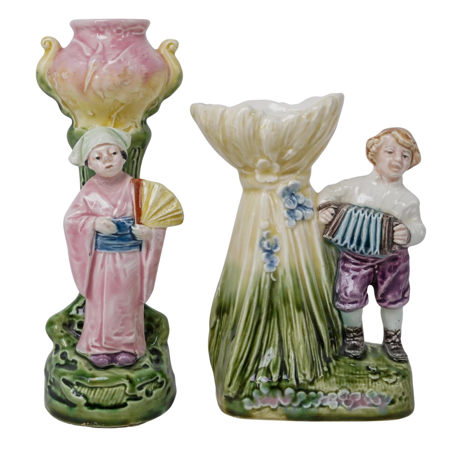 (2 Pc) Majolica Figural Spill Vases: (2 Pc) Majolica Figural Spill Vases 20th c., Austria Austrian figural spill vase depicting a boy in a white shirt and purple trousers playing the accordion while standing next to a vase shaped like cr