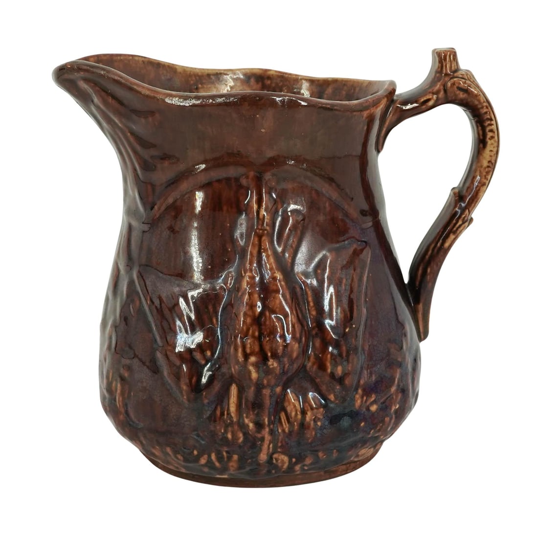 19th Cent. Rockingham Pottery Pitcher: 19th Cent. Rockingham Pottery Pitcher 19th c., USA Antique Rockingham pottery pitcher featuring the distinctive brown glaze over high-relief depictions of a hanging game bird and a fleeing deer, with 