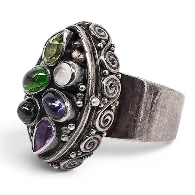 Sajen Sterling Silver & Multi-Gemstone Poison Ring: Sajen Sterling Silver & Multi-Gemstone Poison Ring 1990s-2000s, Indonesian Sajen sterling silver poison ring with hinged oval locket-form top, applied scroll and beadwork decoration, and assorted beze
