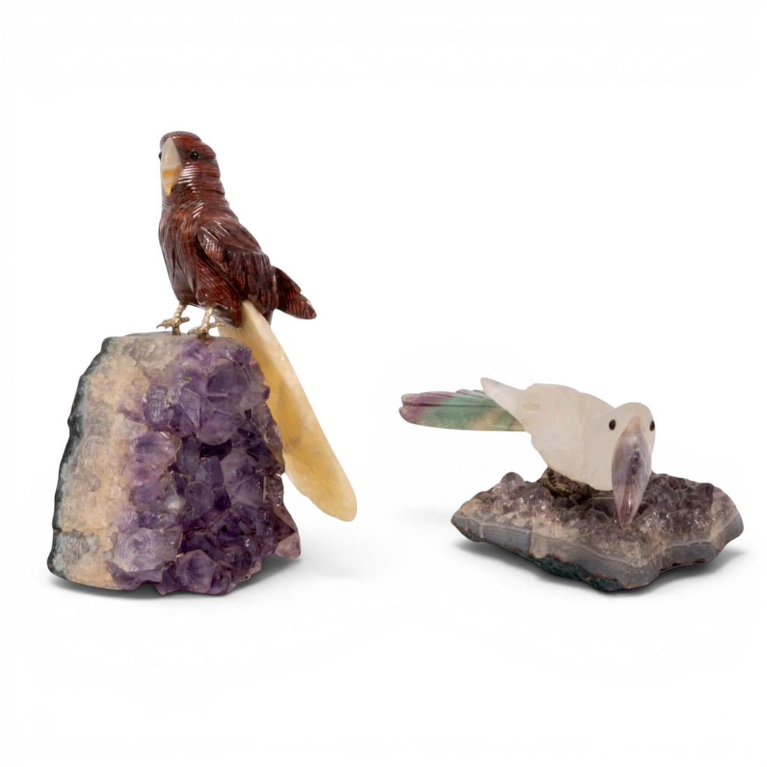 (2 pc) Jasper & Quartz Birds on Amethyst Geodes: (2 pc) Jasper & Quartz Birds on Amethyst Geodes 20th Cent, Likely Brazil Two gemstone bird sculptures hand-carved from jasper (parrot) and quartz (toucan), mounted on natural purple amethyst geode