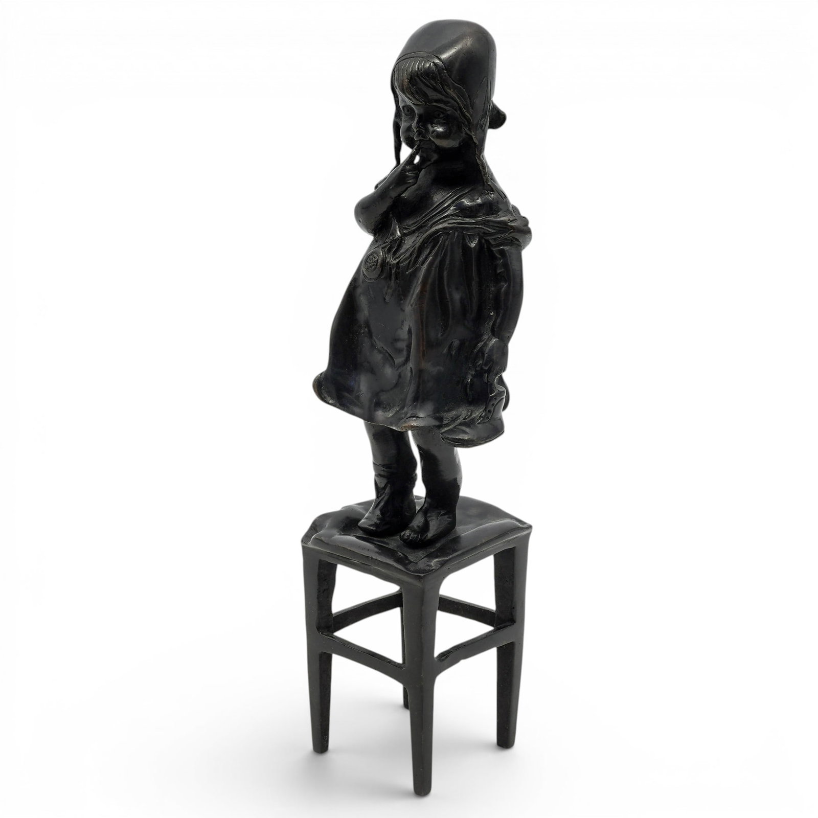 After Juan Clara "Girl on a Stool"Bronze Sculpture: After Juan Clara "Girl on a Stool"Bronze Sculpture 20th Cent., Spanish "Girl on a Stool" depicts a young child in a bonnet standing on a small chair or stool, holding a shoe. H: 11 3/4" W: 3" D: 3"