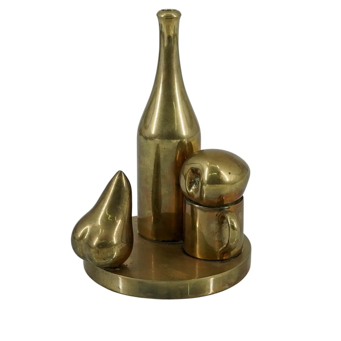 Paul Suttman (American, 1933-1993) Bronze Still Life Sculpture: Paul Suttman (American, 1933-1993) Bronze Still Life Sculpturec. 1973, USACast bronze sculpture featuring a bottle, a mug, and pieces of fruit arranged on a round base. Artist signature on the base. T