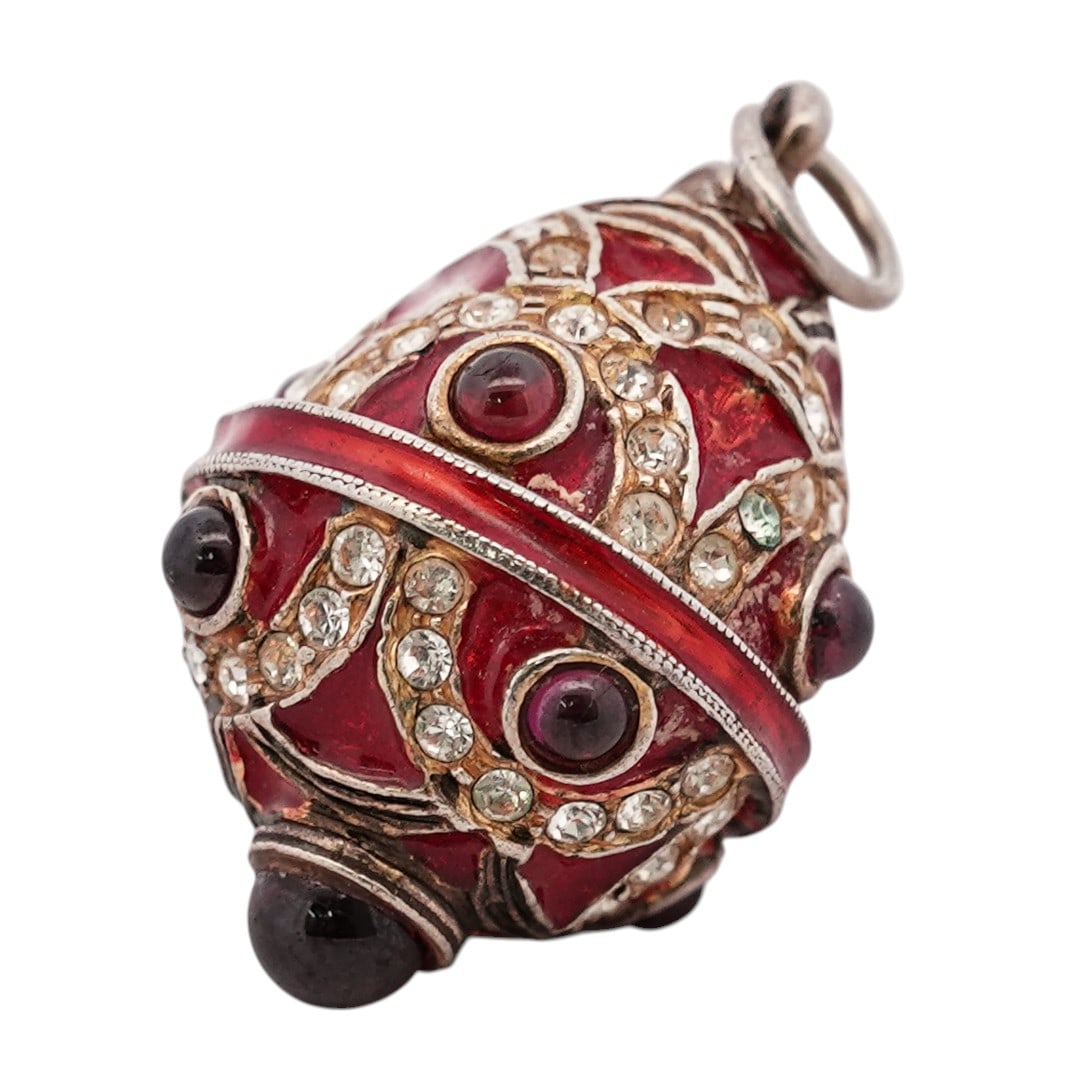Faberge Style Enamel Egg Pendant: Faberge Style Enamel Egg Pendant 1970s-1980s Egg-form pendant with red enamel panels within a gilt metal framework, set with clear stones and cabochon accents. The body is constructed in two halves