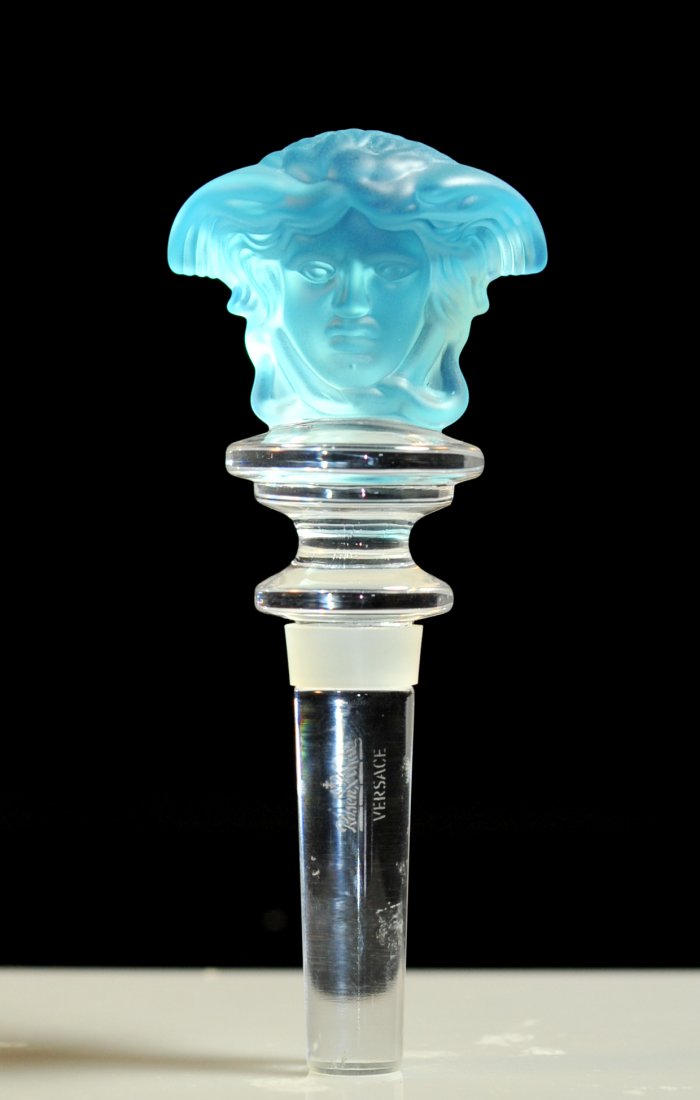 Versace crystal "Double Medusa" sky blue stopper: DESCRIPTION: Versace crystal "Double Medusa" sky blue bottle stopper. Clear crystal shaft with top rubber ring. Tapering and step crystal neck featuring a double sided sky blue Medusa head. No chips o