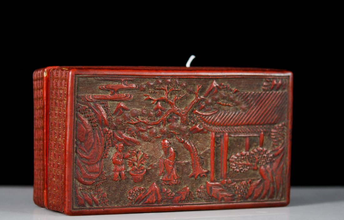 19th Century hand carved Chinese cinnabar box: DESCRIPTION: 19th Century hand carved Chinese cinnabar box. Lid features an relief and raised scene of an elder and young man tending a potted plant. The courtyard in which they stand is surrounded by