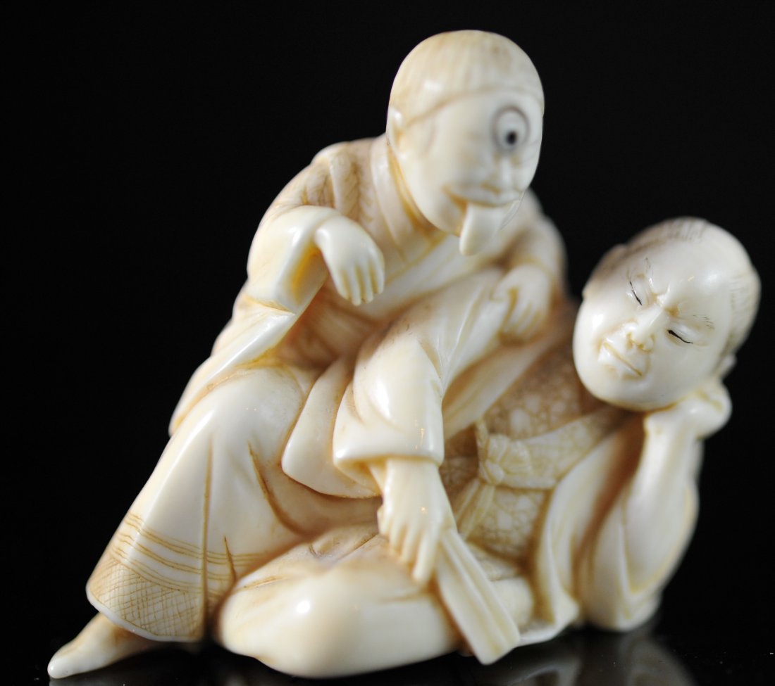Antique Chinese hand carved ivory netsuke. Signed: DESCRIPTION: Antique Chinese hand carved ivory netsuke. Features a robed man laying at rest, a second man leans over his body with his tongue out as if he is teasing the resting man. The details on th