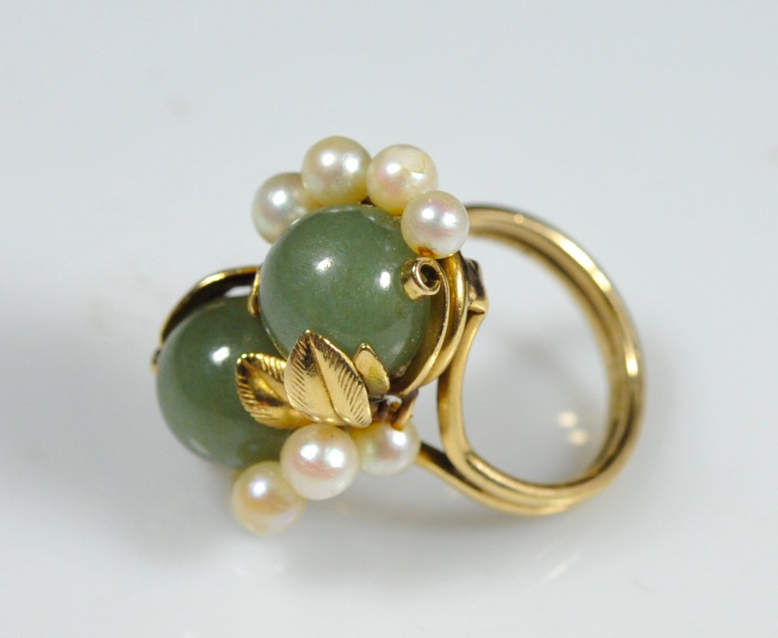 14k, jade and pearl floral evening ring. Signed: DESCRIPTION: 14k, jade and pearl floral evening ring. Features two 10mm jade balls hugged by 14k leaf foliage accented by nine natural sea pearls. Double band design stamped "14k" and signed "Mings" 1