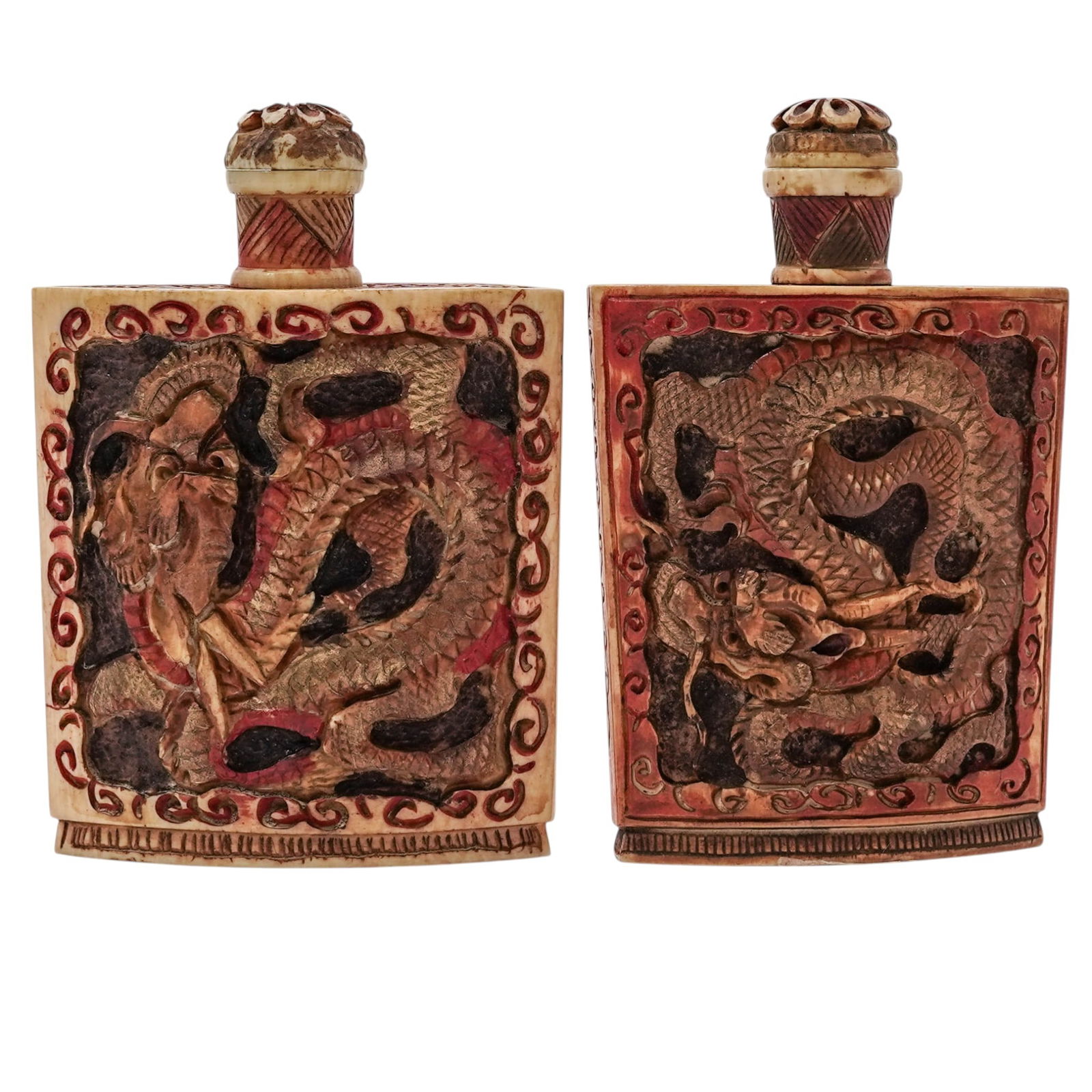 (2 Pc) Chinese Carved Bone Dragon Snuff Bottles: (2 Pc) Chinese Carved Bone Dragon Snuff Bottles20th century, ChineseChinese Carved Bone Snuff Bottles feature intricate dragon motifs in gold relief against a dark background, framed by a reddish-pink