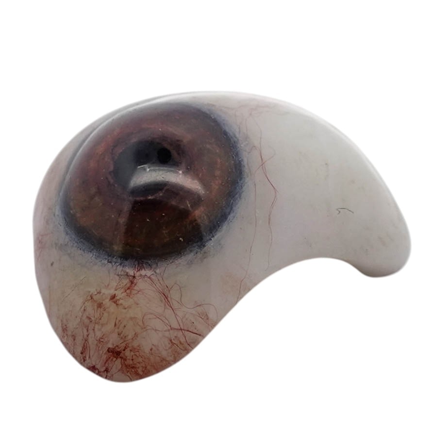 Vintage Glass Prosthetic Eye in Fitted Case: Vintage Glass Prosthetic Eye in Fitted CaseEarly–mid 20th centuryHand-blown glass prosthetic human eye with a realistically rendered brown iris and dark limbal ring beneath a clear convex cornea. Th