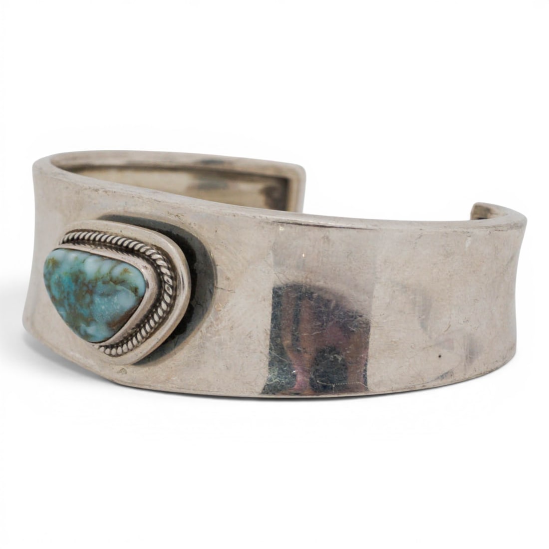 P. Sanchez Navajo Sterling Silver & Turquoise Cuff Bracelet: P. Sanchez Navajo Sterling Silver & Turquoise Cuff Bracelet 1980s-1990s, USA Sterling silver cuff bracelet with a single triangular turquoise cabochon set in a rope-twist bezel on a wide, slightly tap