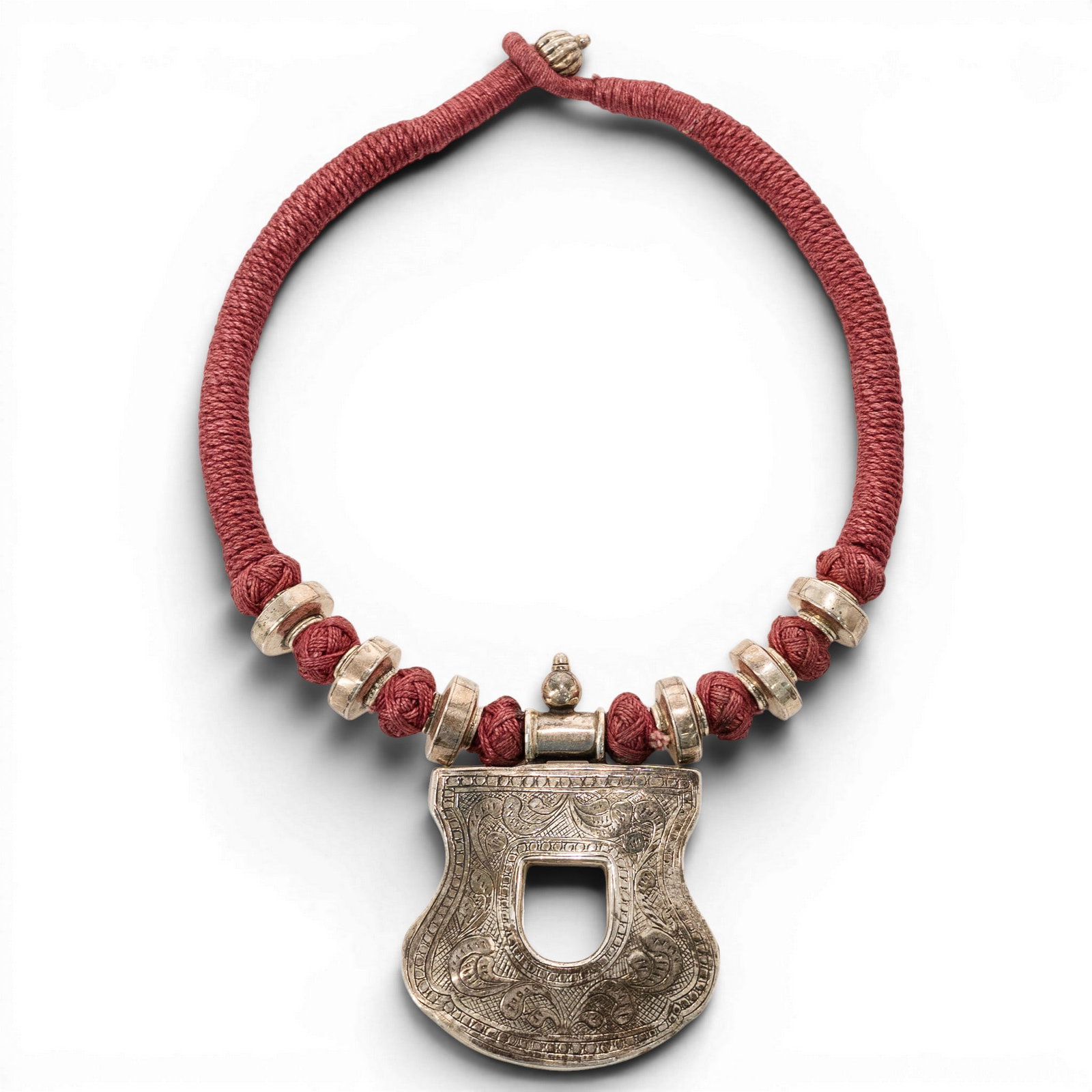 Sterling Silver Repousse Pendant Cord Necklace: Sterling Silver Repousse Pendant Cord Necklace Late 20th Century Sterling silver cord necklace featuring a red wrapped cord with sterling silver bead accents and a large shaped repoussé pendant. Pend
