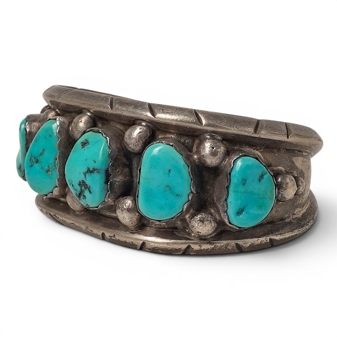 A Milton Lasiloo Navajo sterling silver and turquoise cuff bracelet: A Milton Lasiloo Navajo sterling silver and turquoise cuff bracelet Late 20th century Stamped: M.L. / Sterling A heavy cuff with four vertically arranged turquoise cabochons in sawtooth bezels within 