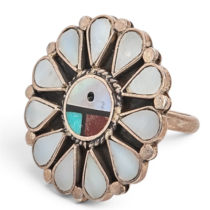 A Zuni Pueblo sterling silver and multistone Sunface ring: A Zuni Pueblo sterling silver and multistone Sunface ring Late 20th century Unmarked Tests for sterling. An oval cluster ring centered by a mother of pearl, turquoise, jet, and coral Sunface mosaic in