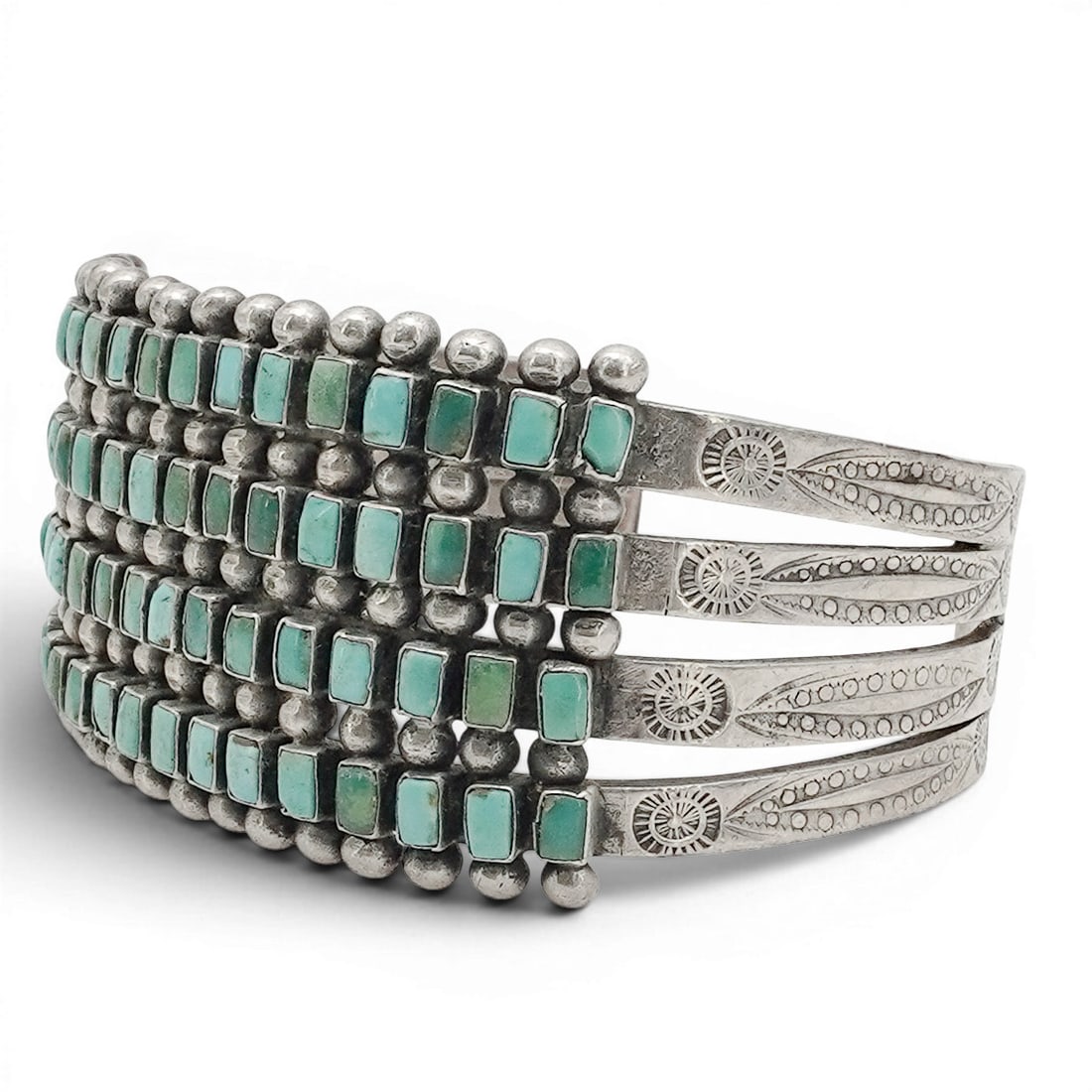 A Zuni sterling silver and turquoise cuff bracelet: A Zuni sterling silver and turquoise cuff bracelet Late 20th century Unmarked. Tests for sterling. A wide cuff with four graduated rows of petit point turquoise in sawtooth bezels, separated by silver