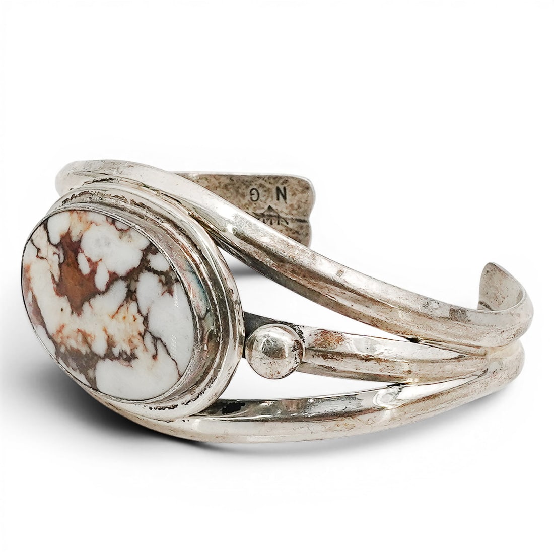 A Nelson Garcia Kewa sterling silver and White Buffalo cuff bracelet: A Nelson Garcia Kewa sterling silver and White Buffalo cuff bracelet Late 20th/ 21st century Stamped: N.G. / Sterling A three-rail cuff set with a large oval White Buffalo cabochon in a smooth bezel. 