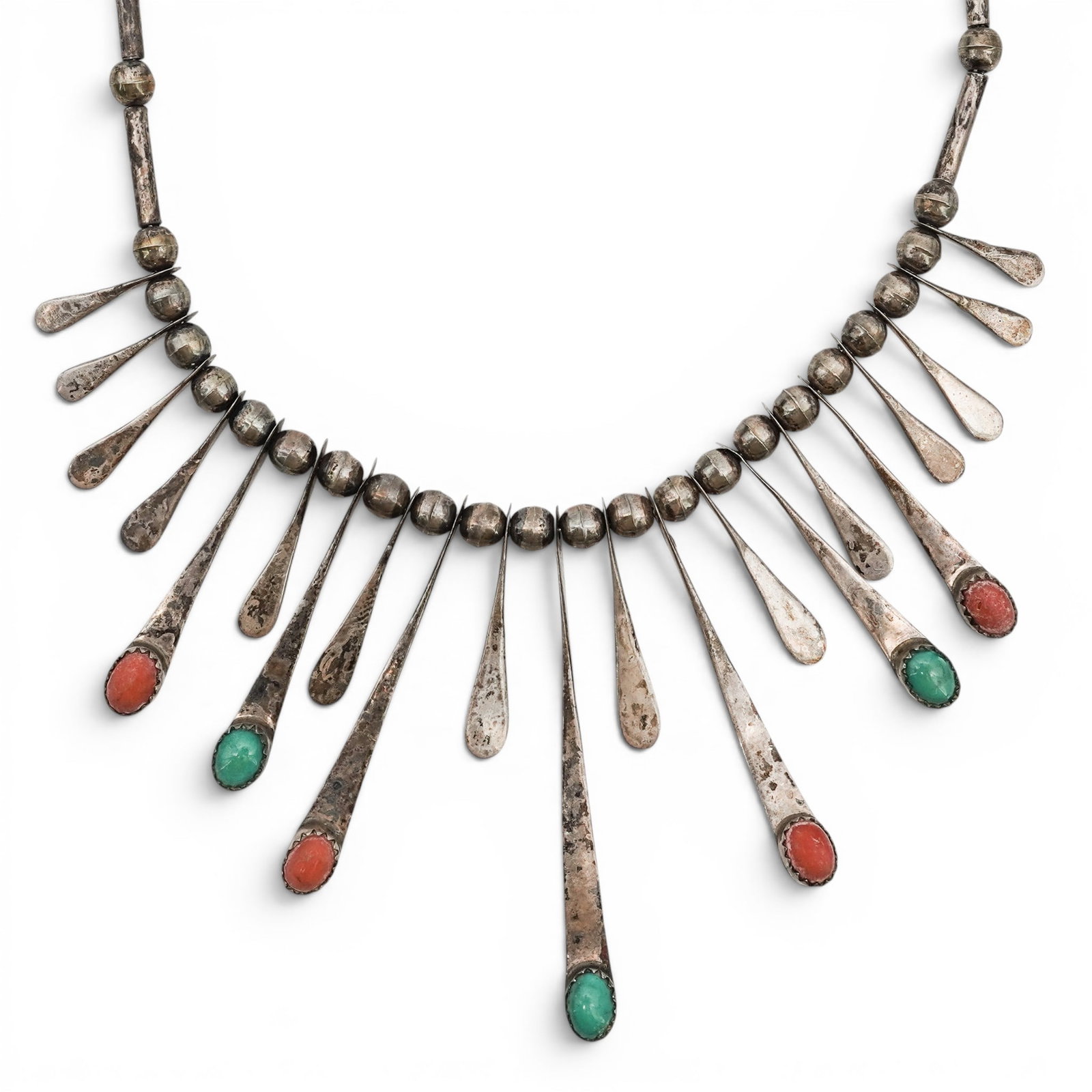 A Southwest sterling silver, turquoise, and coral necklace: A Southwest sterling silver, turquoise, and coral necklace Early/mid-20th century Unmarked. Tests for sterling. A double strand bench bead necklace with radiating stamped silver fringe drops terminati