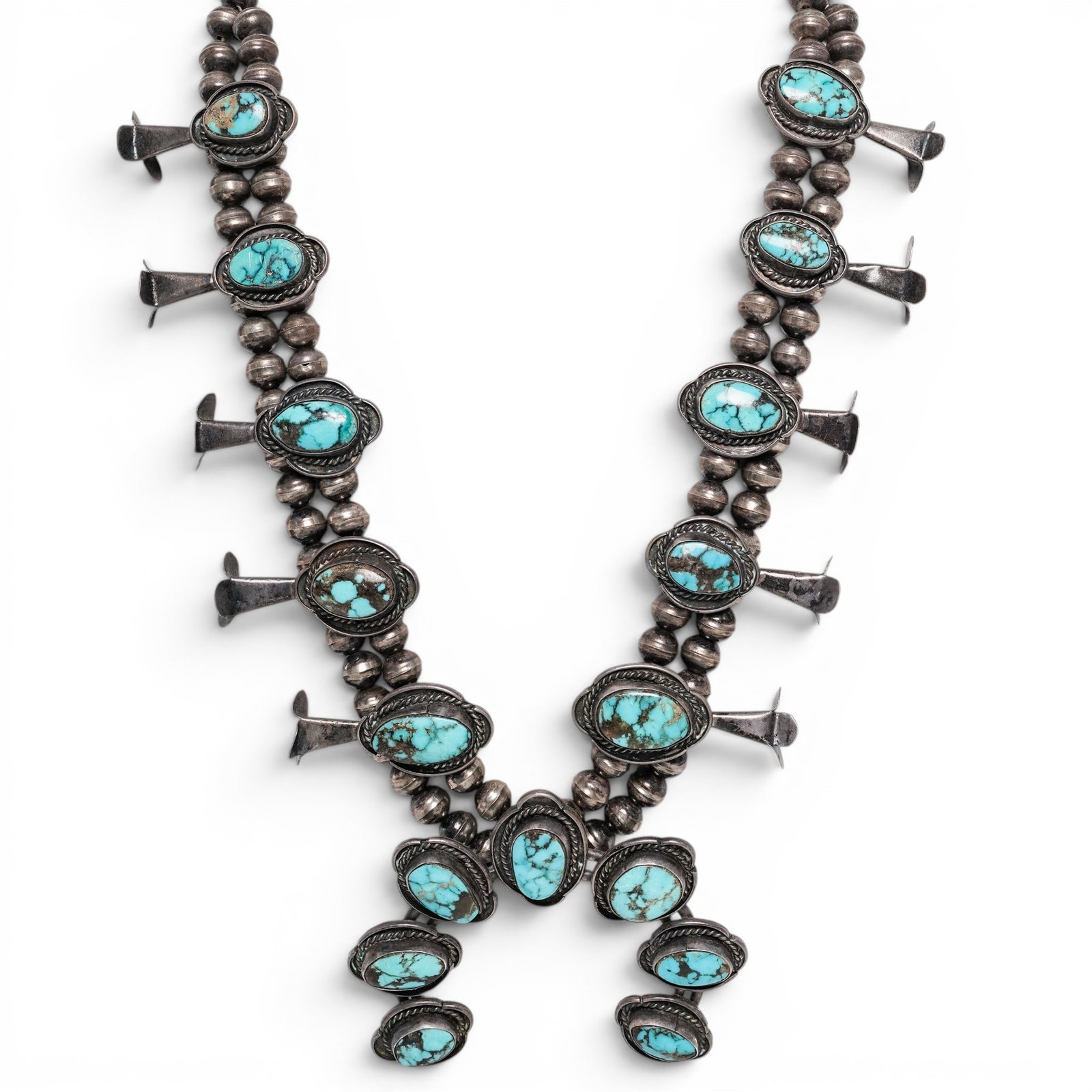 A Southwest sterling silver and turquoise squash blossom necklace: A Southwest sterling silver and turquoise squash blossom necklace Mid/late 20th century Stamped: Sterling A double strand bench bead squash blossom necklace with crescent naja pendant, oval bezel-set 
