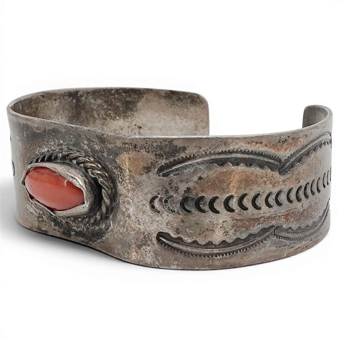 A Southwest sterling silver and coral cuff bracelet: A Southwest sterling silver and coral cuff bracelet Late 20th century Tests for sterling. A wide cuff set with a marquise-shaped coral cabochon in a smooth bezel with twisted wire surround and overall