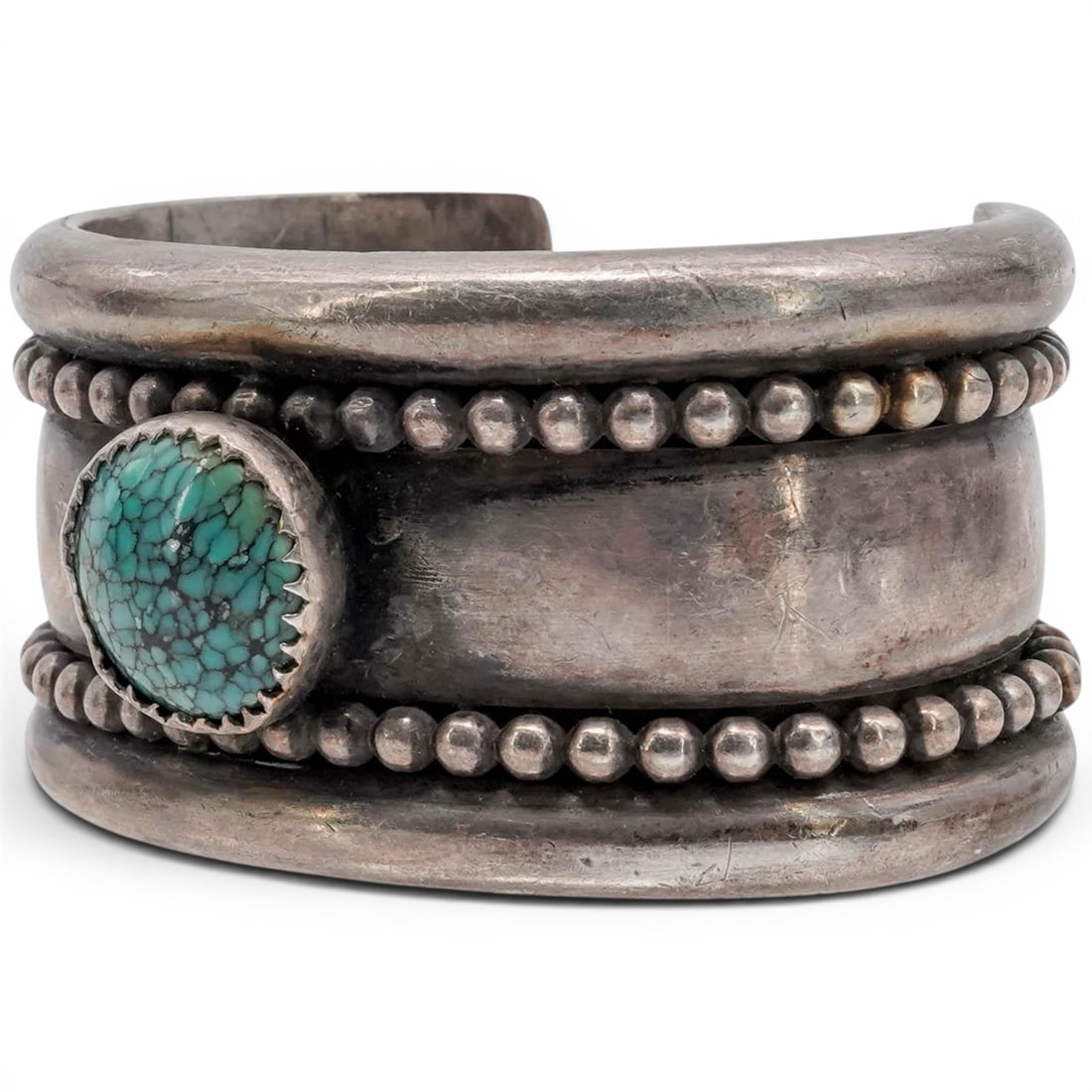 A Southwest sterling silver and turquoise cuff bracelet: A Southwest sterling silver and turquoise cuff bracelet Late 20th century Tests for sterling. A heavy three-band cuff with rounded outer rails, applied silver beadwork, and a round turquoise cabochon 
