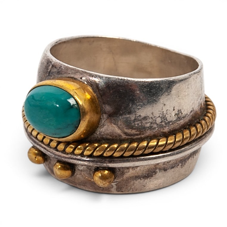 A Southwest sterling silver, brass, and turquoise ring: A Southwest sterling silver, brass, and turquoise ring Late 20th century Stamped: Sterling A wide tapered shank ring set with an oval turquoise cabochon in a brass bezel, with twisted brass wire and a