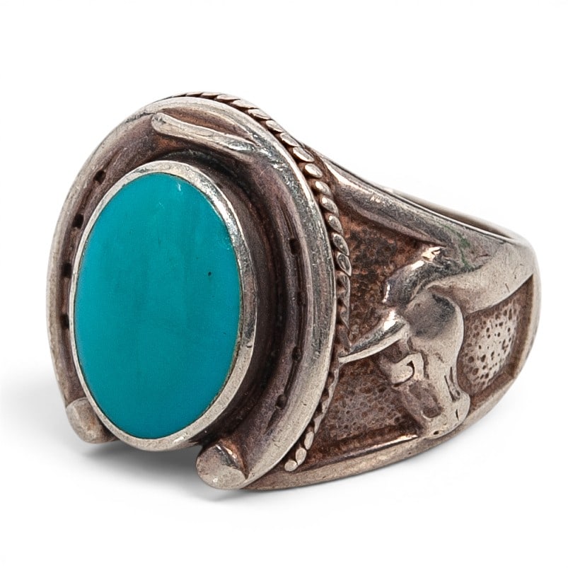 A Southwest sterling silver and turquoise horseshoe ring: A Southwest sterling silver and turquoise horseshoe ring 1984 Stamped: 84 STER / [unidentified hallmark] A substantial ring set with an oval turquoise cabochon in a smooth bezel within a raised horses