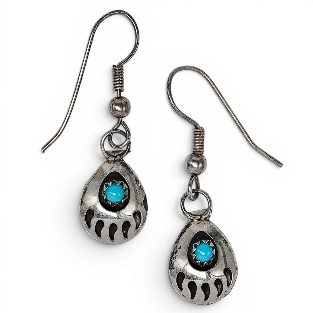 A pair of Southwest sterling silver and turquoise bear paw dangle earrings: A pair of Southwest sterling silver and turquoise bear paw dangle earrings Late 20th century Unmarked. Tests for sterling. A pair of wire hook dangle earrings, each with an openwork bear paw-form silv