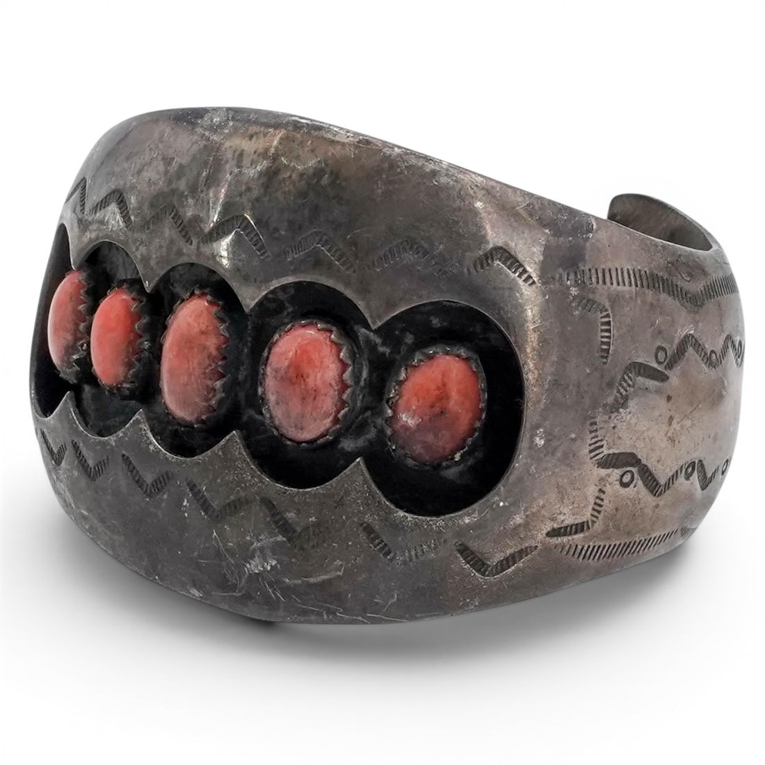 A Pamella Benally Navajo sterling silver and coral cuff bracelet: A Pamella Benally Navajo sterling silver and coral cuff bracelet Late 20th century Stamped: P. Benally / Sterling A wide tapered cuff with five vertically aligned bezel-set oval coral cabochons in a s