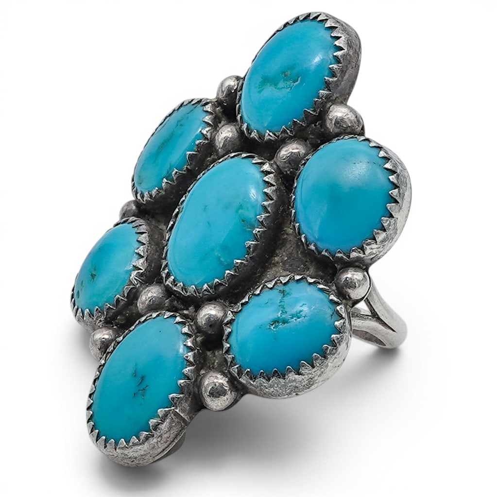 A Southwest sterling silver and turquoise cluster ring: A Southwest sterling silver and turquoise cluster ring Late 20th century Unmarked Tests for sterling. A split-shank cluster ring set with seven turquoise cabochons in sawtooth bezels, arranged in a fl