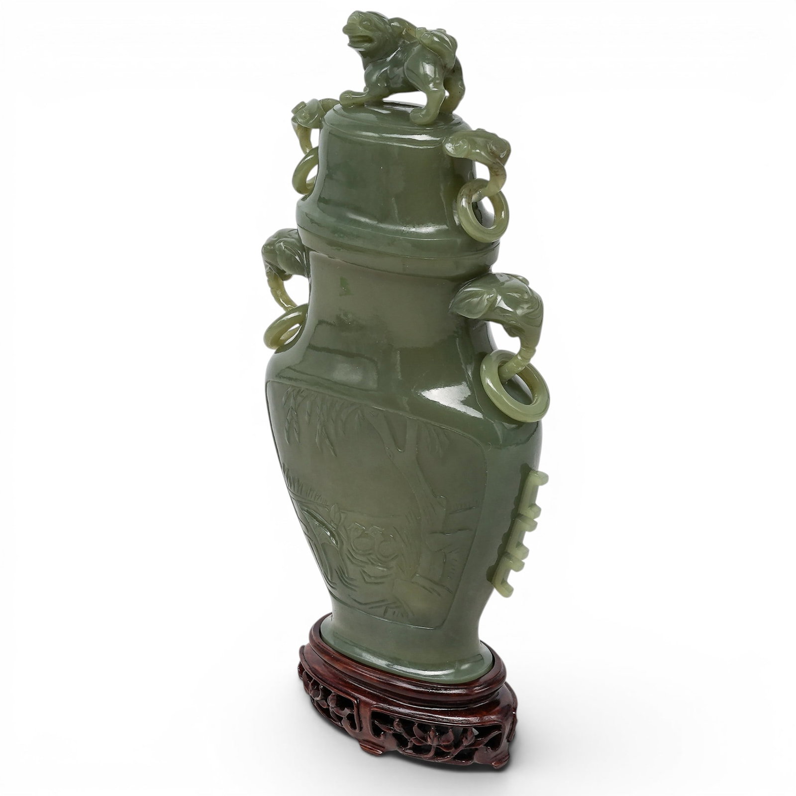 Chinese Carved Jade Lidded Urn With Wood Stand: Chinese Carved Jade Lidded Urn With Wood Stand 20th Cent., Chinese This urn is carved from a translucent celadon-green jade. The body features low-relief carved panel decoration and is adorned with fo