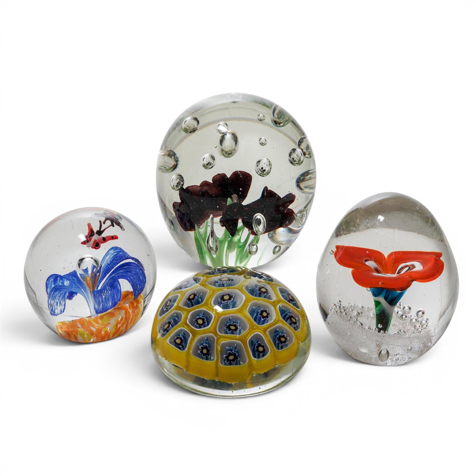 (4pc) Murano Glass Paperweight Group: (4pc) Murano Glass Paperweight Group 20th Cent. The group includes: (1)Purple Lilies.Features deep purple or burgundy sculpted trumpet flowers with green stems. (1)Orange Blossom. Showcases a vibrant 