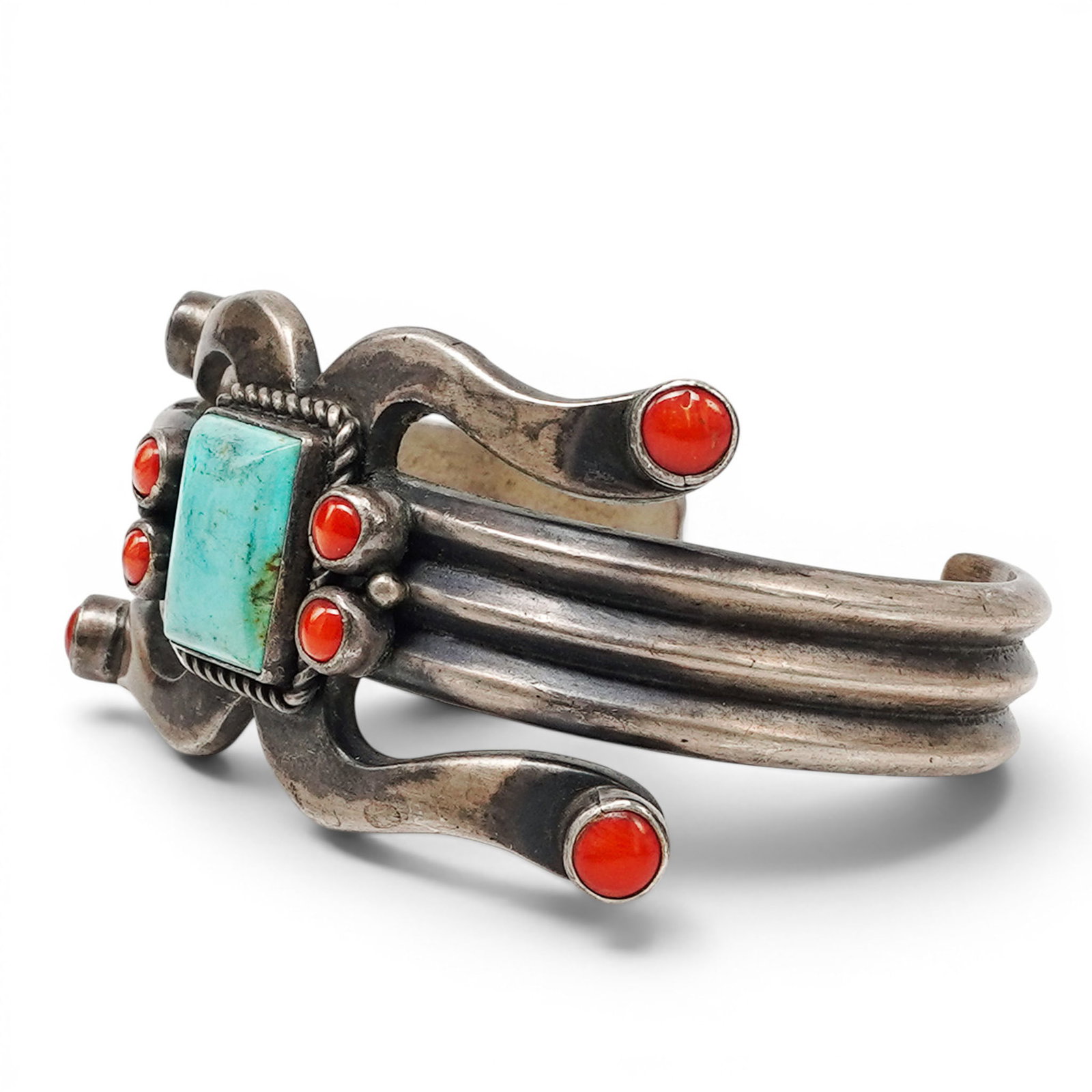 A Dean Brown Navajo Silver, Turquoise, And Coral Cuff Bracelet: A Dean Brown Navajo Silver, Turquoise, And Coral Cuff Bracelet Late 20th century Stamped: D.B. / Sterling. A heavy silver cuff bracelet with a rectangular turquoise stone in a bezel setting, accented 