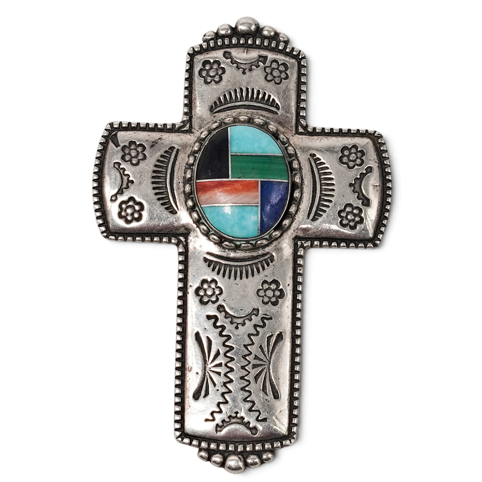 A Navajo Sterling Silver And Multistone Inlay Cross Brooch: A Navajo Sterling Silver And Multistone Inlay Cross Brooch Late 20th Century Stamped: Relios hallmark / .925. A cross-form brooch with geometric multistone inlay roundel at center and engraved Southwe