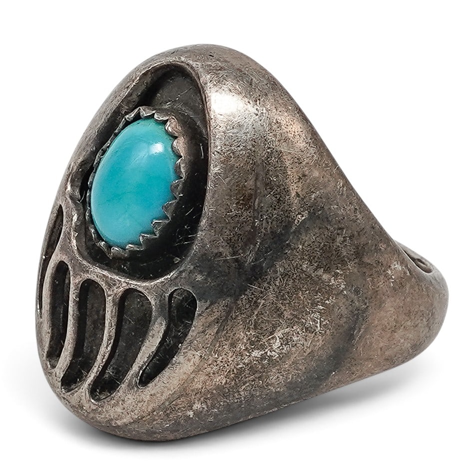 A Navajo Sterling Silver And Turquoise Bear Paw Ring: A Navajo Sterling Silver And Turquoise Bear Paw Ring Late 20th century Unmarked. Tested sterling silver. A heavy cast ring with bear paw motif centered by a bezel-set turquoise cabochon with rope wire