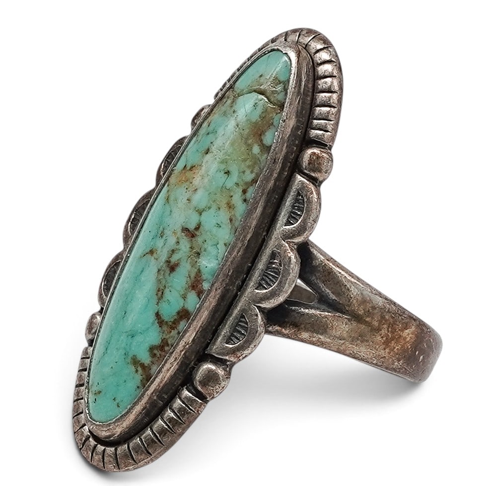 A Bell Trading Post Sterling Silver And Turquoise Split Shank Ring: A Bell Trading Post Sterling Silver And Turquoise Split Shank Ring Late 20th Century Stamped: Bell Trading Post hallmark / Sterling. A ring set with an elongated oval turquoise cabochon in a serrated 
